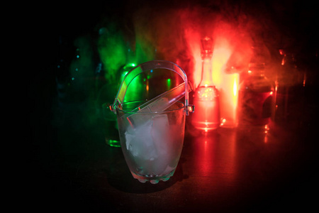 玻璃冰桶上的模糊酒精瓶背景与灯光和烟雾。俱乐部饮料的概念。俱乐部酒吧服务台。准备服务。选择性聚焦