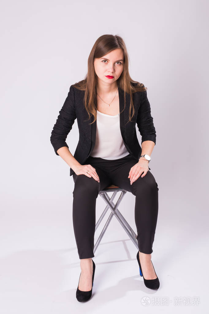 高跟鞋, 坐在椅子上的白色背景的年轻商业妇女的全长工作室肖像照片