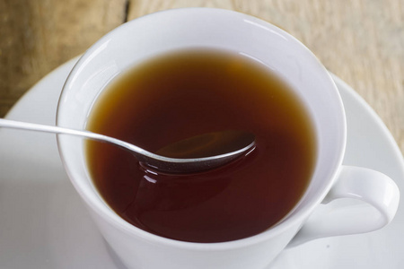用勺子把茶杯里的健康茶合在木桌上