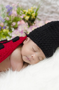 可爱的婴儿的肖像在针织瓢虫服装睡在白色的毯子. 选择性聚焦镜头