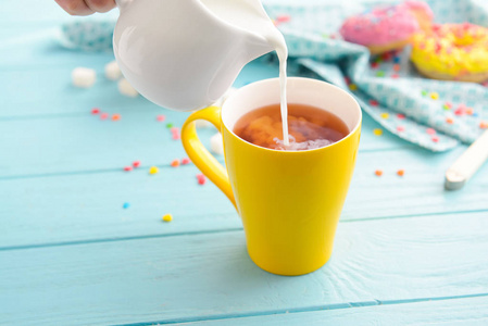 把牛奶倒入木桌上的杯茶中