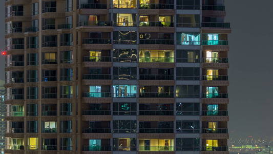 美丽的摩天大楼在傍晚 timelapse 的窗户。现代住宅高层建筑在迪拜码头的看法。人们在公寓里搬家。空中俯视图。平底锅