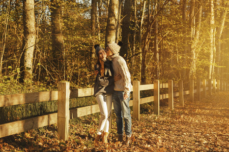 阳光明媚的秋天, 年轻夫妇在公园里穿着暖和的毛衣和羊毛帽子。