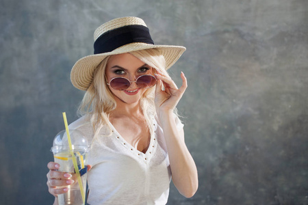 戴草帽的年轻漂亮的金发女郎。夏日风格太阳镜