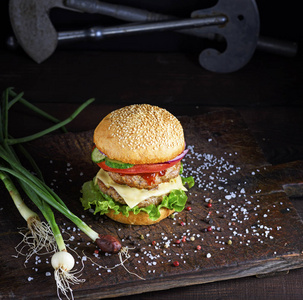 三明治与两个肉肉饼, 奶酪和蔬菜, 一个奶酪汉堡在棕色木板上, 顶部视图