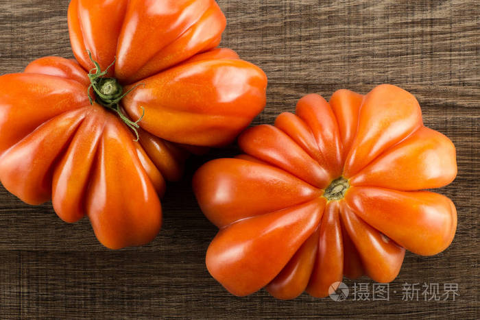 两个牛肉西红柿蝴蝶和花形状在棕木背景上被隔绝的顶部视图一个大成熟