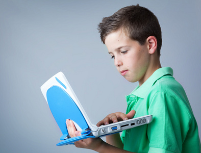 年轻休闲男孩用一台笔记本电脑灰色背景