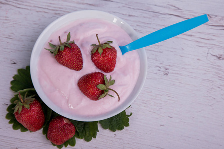 草莓酸奶在一个蓝色背景下的木桌上的新鲜草莓菌丝
