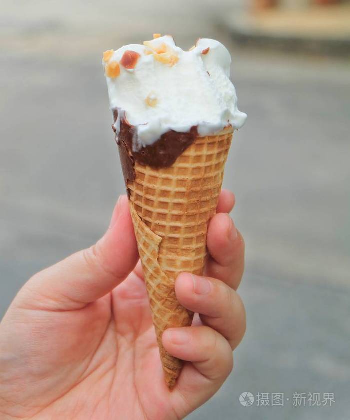 手控股香草冰淇淋与巧克力和坚果华夫桶里
