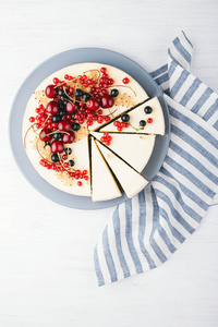 纽约乳酪蛋糕在白色木桌上用浆果。顶部视图。红醋栗, 黑醋栗和樱桃