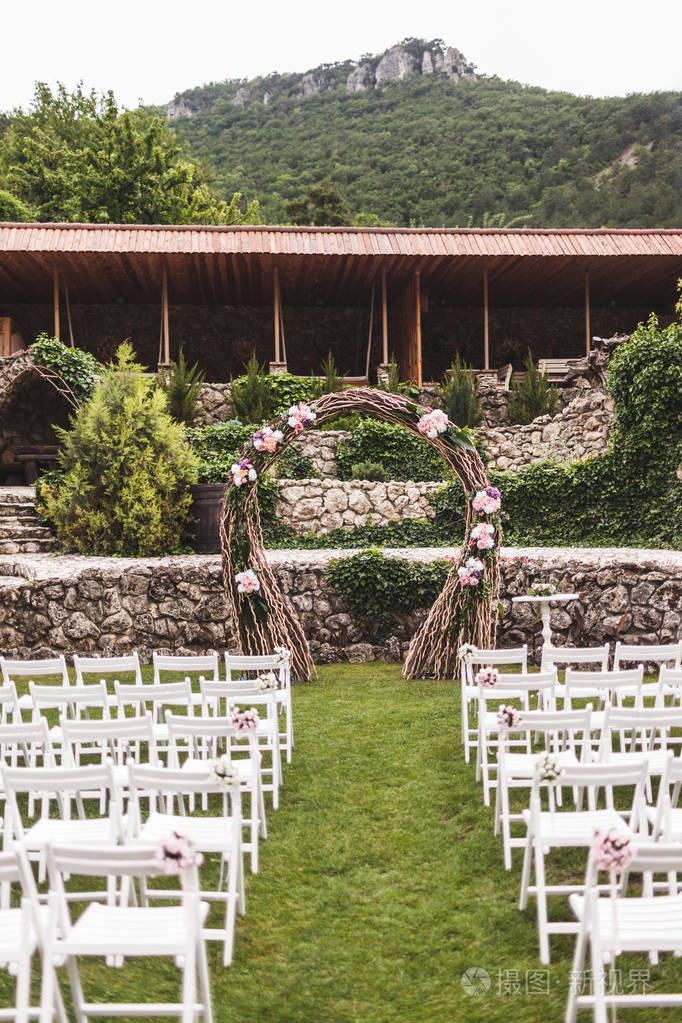 别墅带花拱和木制白椅的温馨乡村婚礼