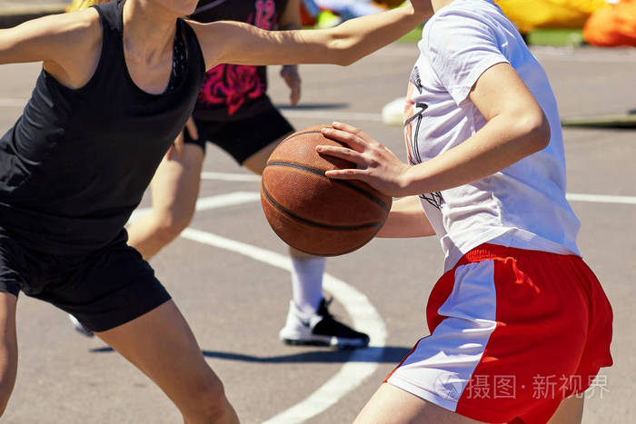 女孩青少年打篮球, 在夏天的街道上。场面战斗为拥有球和交锋