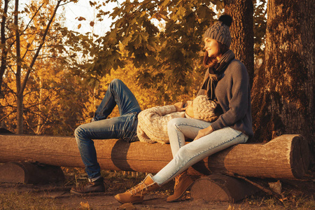 年轻快乐夫妇坐在长凳上秋季公园