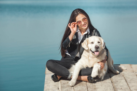 年轻漂亮的女人坐在码头与她的狗.户外最好的朋友照片