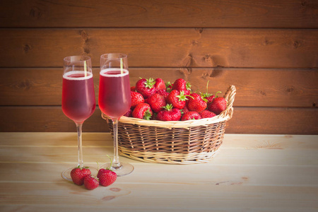 两杯玫瑰香槟和新鲜草莓在柳条篮子里