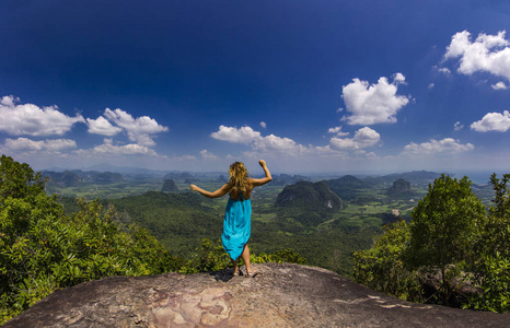 女孩用手站立在岩石在日落与山下面