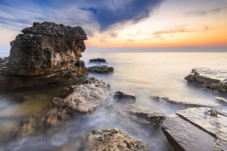 五颜六色的日落在海滩与岩石在亚得里亚海海岸伊斯特拉克罗地亚
