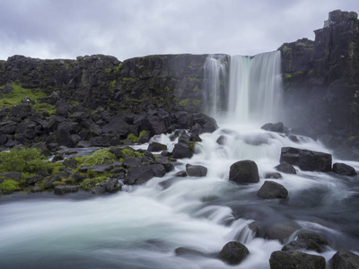 Oxararfoss 瀑布在 Thingvellir 冰岛自然保护区与岩和青苔, 下落从裂缝在中大西洋山脊, 长的曝光运动模