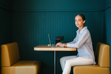 年轻自信的女商人工作在笔记本电脑坐在桌子上现代办公室