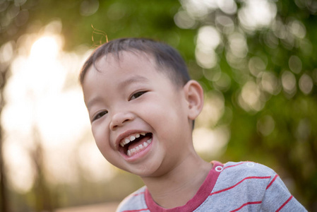 快乐的亚洲男孩在公园里微笑着的亲密。小亚洲儿童肖像照片在公园里