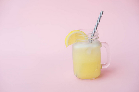 在粉红色背景的玻璃罐子里放柠檬的水果水