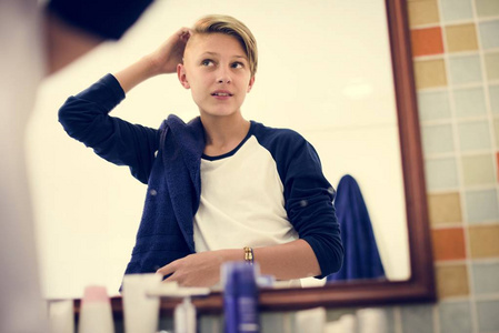 年轻的白种男孩在浴室里设置了镜子的头发