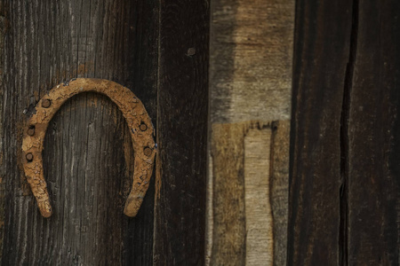 幸运的生锈的老马蹄挂在谷仓。生锈的马蹄在一个旧的和废弃的农场木房子