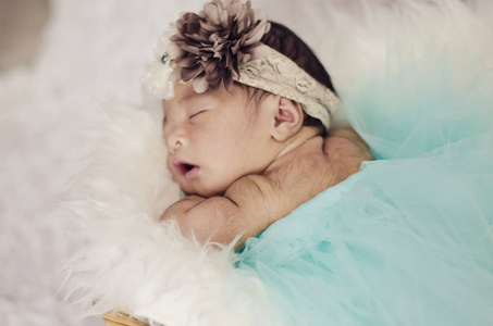 可爱和可爱的婴儿的肖像, 头带睡在篮子里覆盖着毛茸茸的垫子. 母性与育儿理念