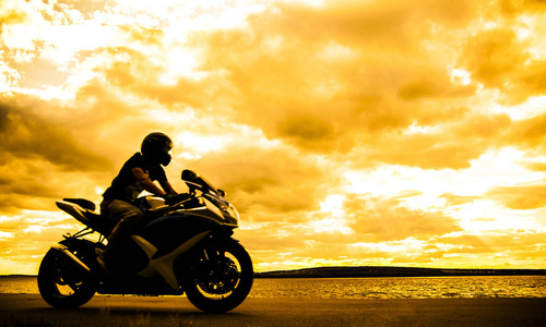 运动的人在日落时骑摩托车的剪影