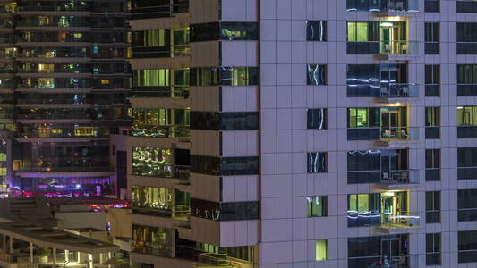 窗户的多层建筑玻璃和钢照明内和移动的人在 timelapse。迪拜滨海现代住宅摩天大楼鸟瞰图