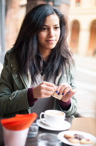 年轻女子在咖啡厅户外喝咖啡。景深浅