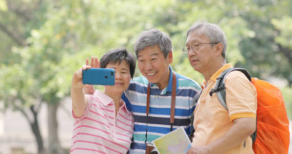 资深朋友一起去旅行和采取自拍用移动电话