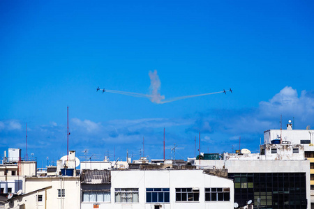 明亮的蓝天与飞行飞机和白色足迹在城市之上照片