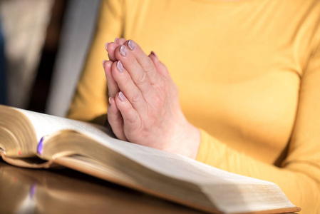 关闭的妇女祈祷她的手在圣经