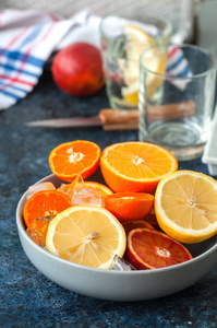 混合新鲜成熟的柑橘类水果作为血橙, mandarines, 柠檬与冰块在一个碗上的蓝色石头背景