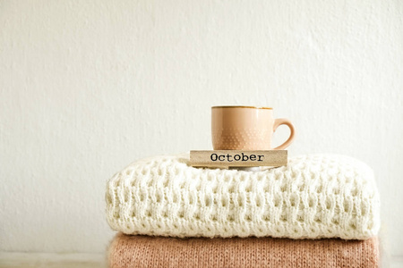 10月字写在木制日历, 卡布奇诺咖啡杯, 一束针织保暖毛衣与不同的针织图案折叠堆叠。秋季冬季针织品。背景, 特写, 复制空间