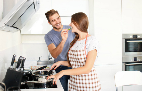 快乐的年轻夫妇,一起在家里的厨房里煮饭的肖像照片