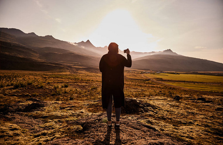在手机上拍照的年轻女孩的剪影冰岛风景。日落在冰岛