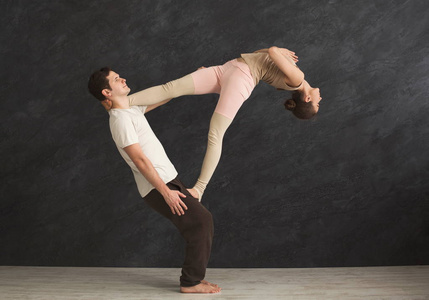 年轻夫妇在垫子上练习 acroyoga