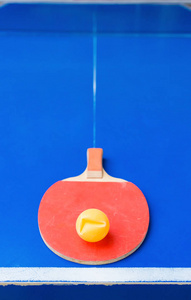 旧乒乓球拍和蓝色乒乓球桌上的凹球