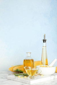 瓶和肉汁船与新鲜的玉米油在桌反对颜色墙壁