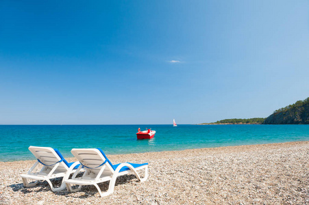 在土耳其凯梅尔的鹅卵石海滩上有两个贵妃休息室。美丽的夏天风景
