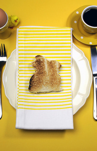 黄色主题快乐复活节早餐表，与兔子兔烤面包和鸡蛋。垂直