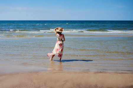 一个戴着帽子的放松女孩正在海滩上散步。波罗的海海岸, 拉脱维亚