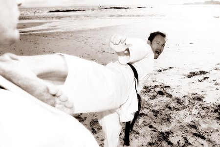 练习空手道在海滩上的年轻成年男性