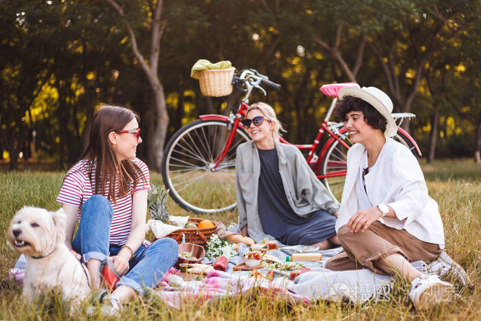 照片 人物 女孩愉快地花费时间在美丽的野餐与小狗在公园以红色自行车