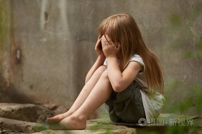 在肮脏的城墙下holen膝的哭泣的女孩孤儿画像
