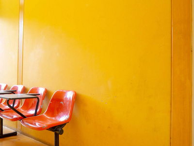 在明亮的黄色背景上等待生动的橙色椅子