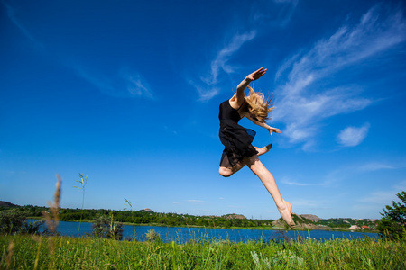 飞跃的一天年轻的女孩做体操跳跃户外照片