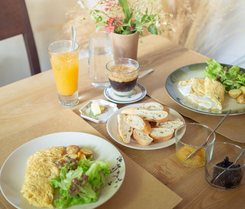美味的早餐与煎蛋, 咖啡, 烤土豆和有机沙拉在白色板材和脆薯片面包, 果酱, 橙汁在木桌上的早晨